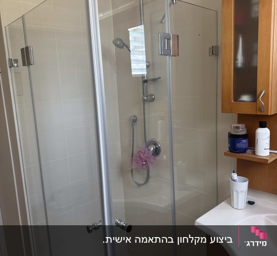 מקלחון זכוכית עם ראש מקלחת ורהיטים בחדר אמבטיה